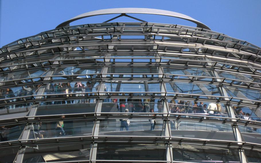 Tourists walk up the ramp and gaze out of the Reichstag cupola in Berlin. The glass and steel structure that tops the seat of German parliament was designed by the noted British architect Norman Foster.