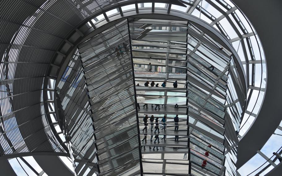 The central mirrored cone of the Reichstag's cupola can be used to draw light into the plenary chamber below. Here, it reflects people on the ramps that spiral around the cupola, offering a 360-degree view of Berlin.