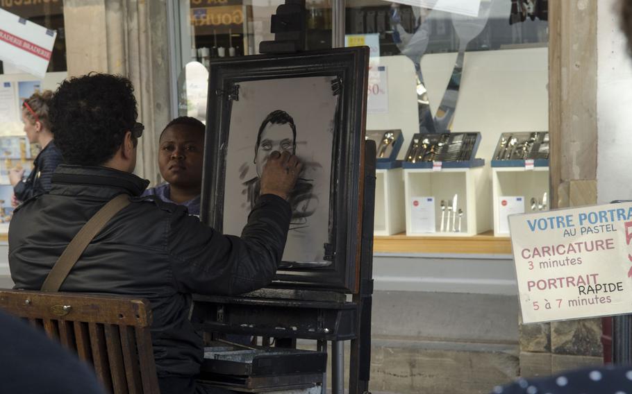 A street artist paints a caricature of a tourist near the Strasbourg Cathedral in Strasbourg, France, Sunday, Sept. 27, 2015.