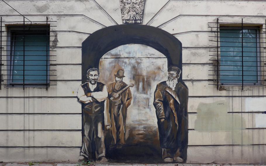 The Lodz street musician Lili Fontelli, center, stands between a Lodz weaver and a Lodz Jew in a giant mural decorating a house on Piotrkowska Street. The side of the building features other famous people of Lodz, Poland, looking out of widows. And because it is next to a park, the house is known as the Tenement House Under the Chestnuts.