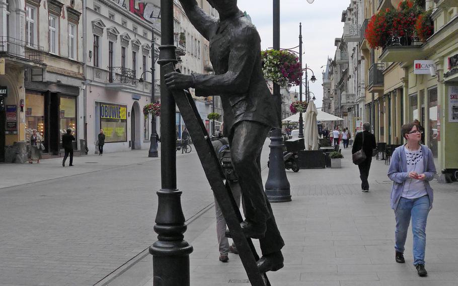 A statue of a man getting ready to screw in a light bulb stands on Piotrkowska Street in Lodz, Poland. It is one of many statues on the city's main pedestrian shopping street. Unveiled in 2007, it marked the 100th anniversary of the city's first electric streetlight.