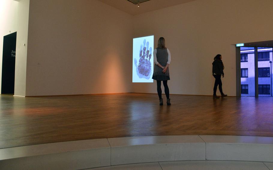 A visitor to MMK 1 looks at Raqs Media Collective's "Untold Intimacy of Digits," a video projection on display at the Frankfurt, Germany, museum.