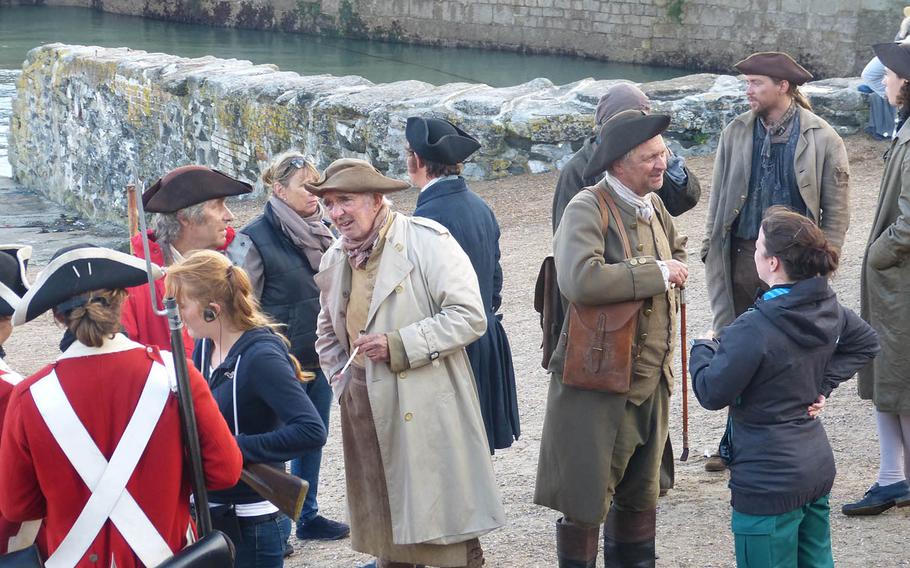 It's a mix of 18th-century-correct costumes and modern-day casual wear as crew members share the setting of  a scene with actors during a break in filming.
