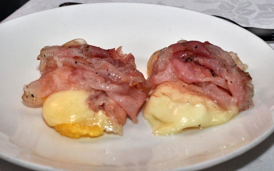 Polenta topped with cheese and bacon is one choice from the appetizer list at Trattoria Da Carmelo in Pasiano, Italy.