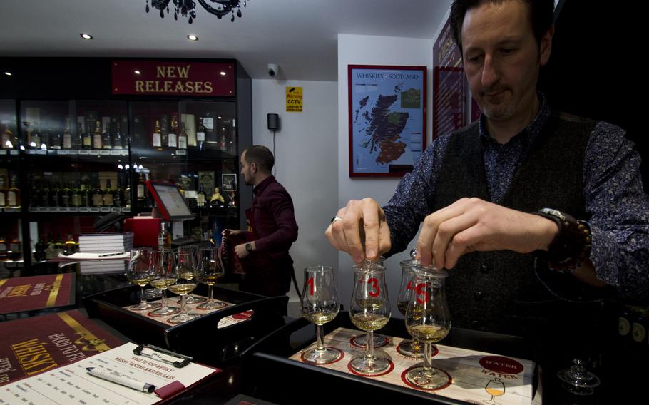 An employee at Hard to Find Whisky places tops on two glasses of scotch on Saturday, Jan. 16, 2016, in Birmingham, England. Located near the Jewellery Quarter of the city, the shop offers informative whisky tastings.