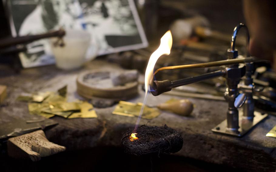 A guide at the Museum of the Jewellery Quarter demonstrates how jewelers can blow air through a pipe to redirect a flame for making jewelry on Saturday, Jan. 16, 2016, in Birmingham, England. The museum is located in the workshop of a former jeweler that closed in the 1980s.