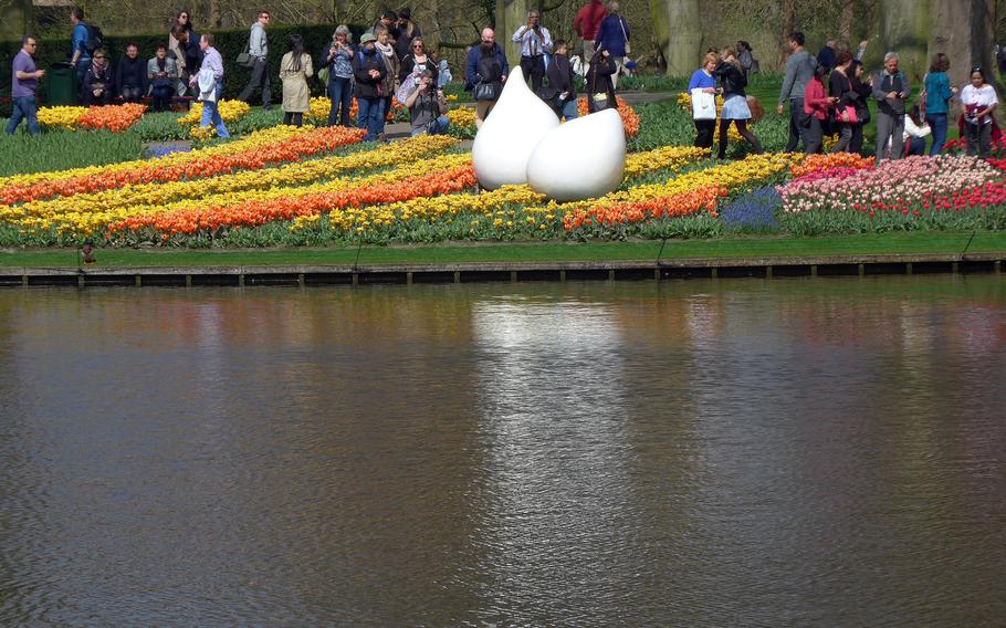 Visitors to Keukenhof walk past rows of flowers and a sculpture, April 10, 2015. The Dutch bulb growers plant millions of tulip, crocus, amaryllis, hyacinth, and daffodil bulbs for the annual show. 