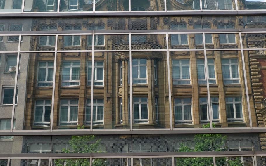 The facade of an old Frankfurt building is reflected in the glass facade of a modern building, as seen from a sightseeing tour bus through the city.