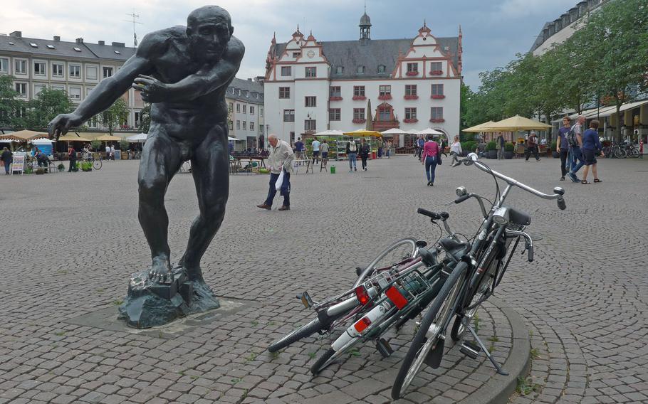 The "Berserker" statue by Waldemar Grzimek stands on the northwestern corner of Darmstadt's market place. In the background is the old Rathaus, or city hall. It was built in the late 16th century but was destroyed in World War II. Rebuilt, it now houses the  popular Ratskeller microbrewery.