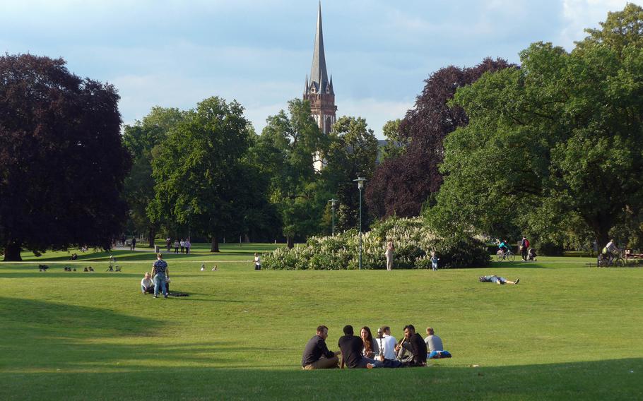People enjoy a sunny summer day in the Herrngarten, the former royal park that is adjacent to the university and popular with its students. The steeple of St. Elizabeth's Church can be seen in the distance.