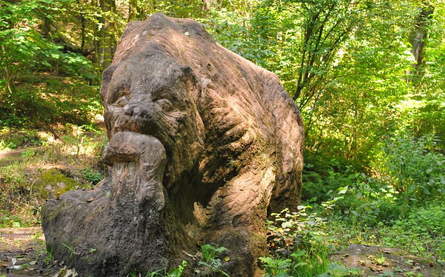 A bear carved from stone stands outside the Bear Cave along the Felsenwanderweg.