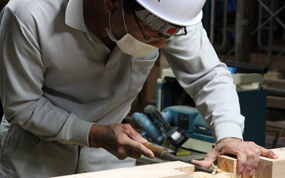 A worker shaves down a wooden joint to be used in the nearly 100-year-old post and beam Tsukayama Distillery in Nago. The awamori distillery is undergoing a five-year, $3.5 million renovation project that's expected to be completed in September.