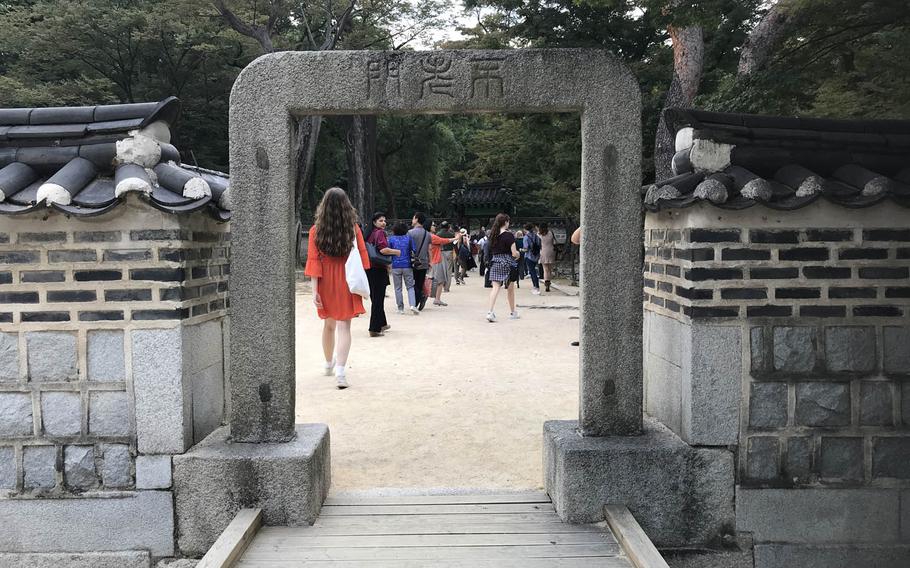 Tourists pass through the Gate of Eternal Youth in the Secret Garden behind the Changdeokgung Palace in Seoul on Sunday, Oct. 8, 2017.