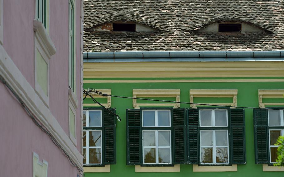 Sibiu, Romania, is a colorful city, with many of its old buildings painted in a variety of colors. The eye-like attic openings sometimes makes it look like the buildings have faces.