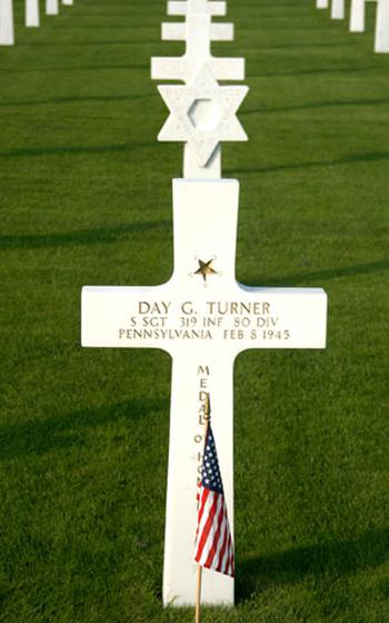 An American flag decorates the grave of Staff Sgt. Day G. Turner, a World War II Medal of Honor recipient, at Luxembourg American Cemetery. Behind Turner’s cross is a Star of David, marking the grave of a Jewish service member.