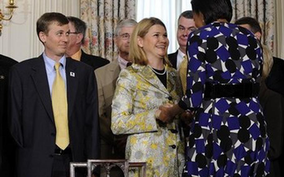 First lady Michelle Obama speaks, right, talks with Sarah Wade, center, wife of Army Sgt. Ted Wade, left, who was wounded in Iraq, in the State Dining Room of the White House  in Washington, Wednesday, May 5, 2010, after President Barack Obama  signed the Caregivers and Veterans Omnibus Health Services Act.