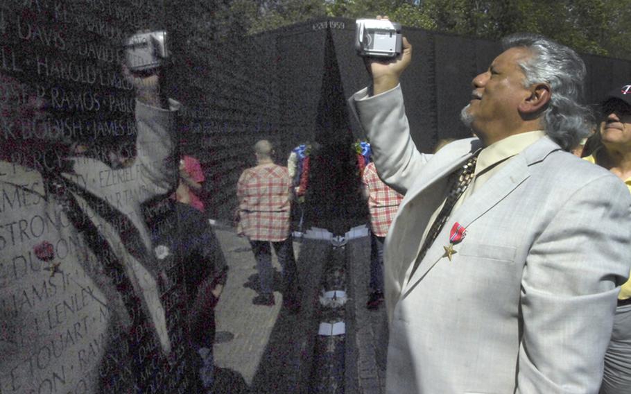 Antonio Martinez takes video of the name of his friend, Joe Billy McNett, on the Vietnam Wall.