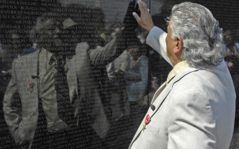 After receiving the Bronze Star with "V" for valor, Antonio Martinez touches the name of his friend, Joe Billy McNett, on the Vietnam Veterans Memorial. McNett was killed in the November 12, 1970 battle for which Martinez was honored.