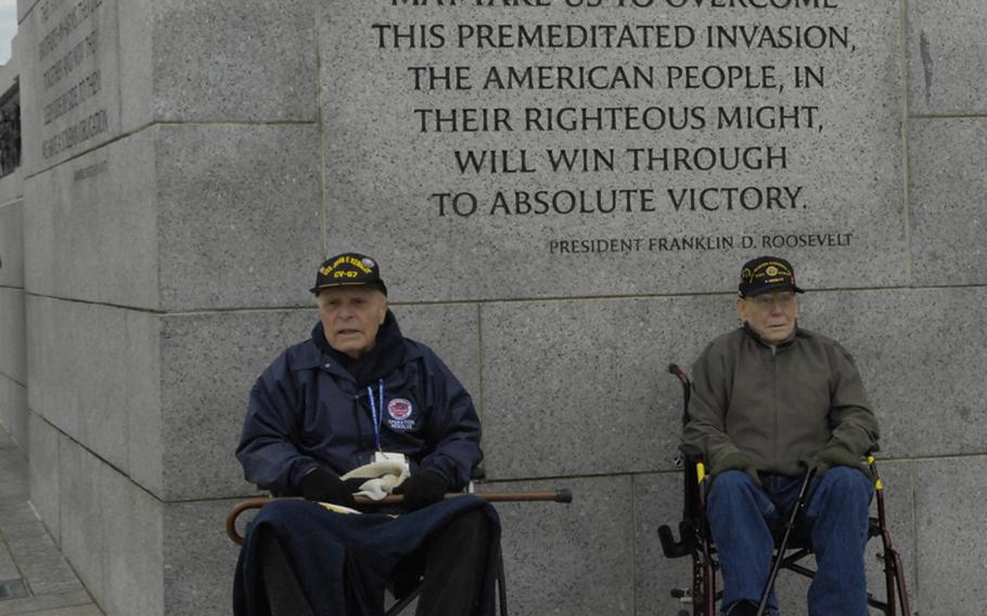 Two veterans take a break from the chilly wind by the Pearl Harbor section of the WWII Memorial.