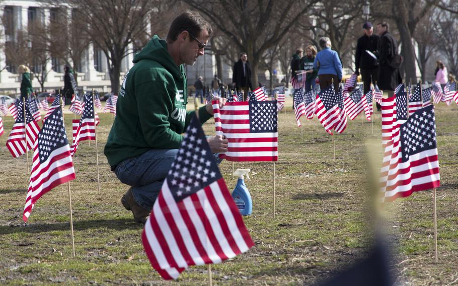Navy veteran Jeff Hensley, a member of Iraq and Afghanistan Veterans of America (IAVA), unfurls flags on the National Mall in Washington, D.C., on March. 27, 2014. A total of 1,892 flags were planted, each representing the number of veterans and servicemembers estimated to have committed suicide so far in 2014.