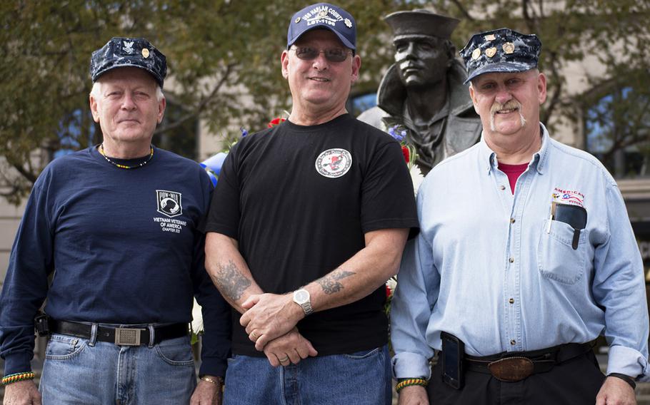 Brothers Jim Miller, John Rosetti and Al Miller, left to right, all of them U.S. Navy Vietnam veterans, pose for a photo in front of the Lone Sailor on Veterans Day, Nov. 11, 2014. at the U.S. Navy Memorial in Washington, D.C.