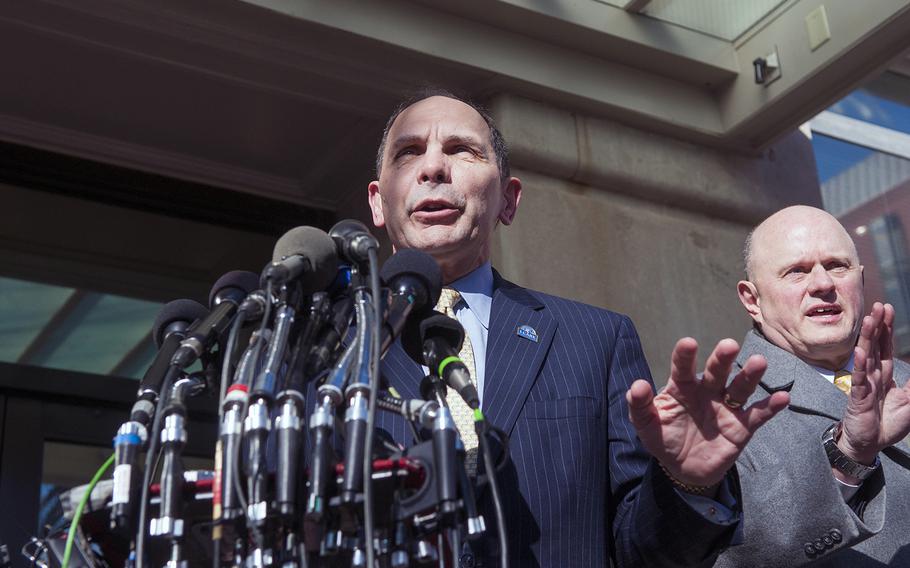 Veterans Affairs Secretary Bob McDonald answers questions outside the VA headquarters building in Washington, D.C., on Tuesday, Feb. 24, 2015. At right is McDonald's Media Relations Director James Hutton trying to keep order among the journalists vying to ask questions.