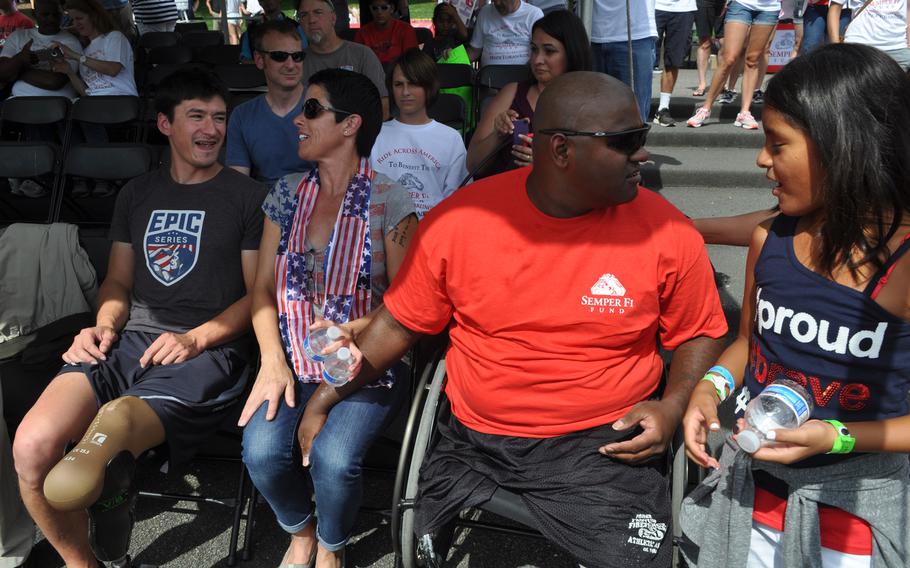 Former Marine Toran Gaal, red shirt, sits with his wife, Lisa Graves-Gaal, second from left, his step-daughter, Isabella Graves, 9, and fellow wounded Marine Brian Riley, far right, on Sunday after Gaal completed a cross-country handcycle trip. 