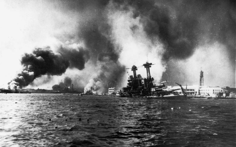 The U.S. Navy battleship USS California slowly sinks alongside Ford Island, Pearl Harbor, Hawaii, as a result of bomb and torpedo damage, December 7, 1941. The destroyer USS Shaw is burning in the floating dry dock YFD-2 in the left distance. The battleship USS Nevada is beached in the left-center distance.
