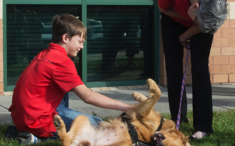 Donovan Nordstrom, 12, plays with Jessi before the start of the Warrior Canine Connection graduation on Oct. 7, 2017.