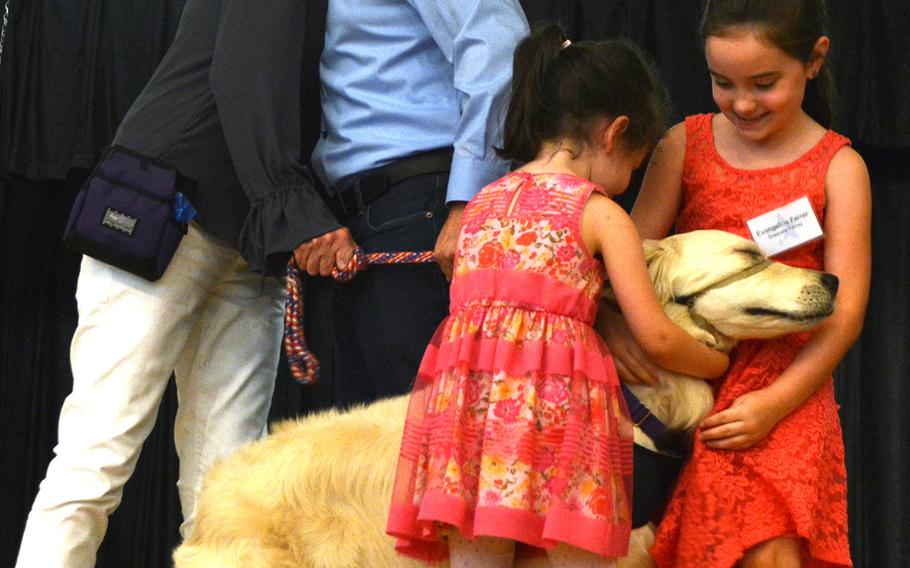 USAF Staff Sgt. Mack Ferrer hugs puppy parent Diane Cadenhead while Ferrer's daughters hug service dog Judy.