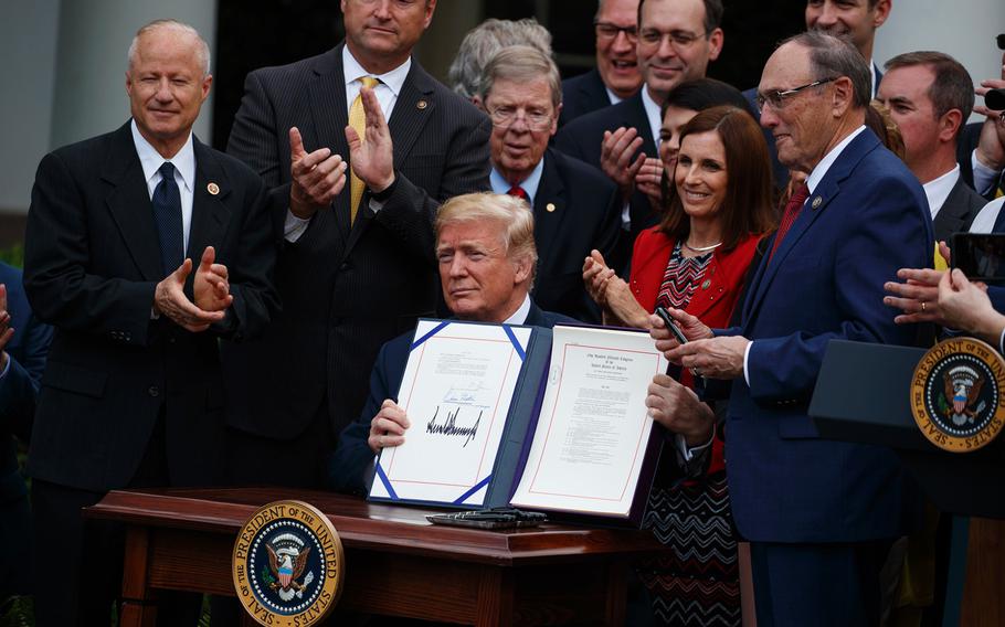 President Donald Trump shows off the "VA Mission Act" during a signing ceremony in the Rose Garden of the White House, Wednesday, June 6, 2018, in Washington. 
