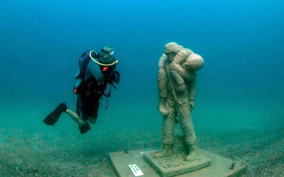 A diver next to the Circle of Heroes Veterans Memorial in the Gulf of Mexico.