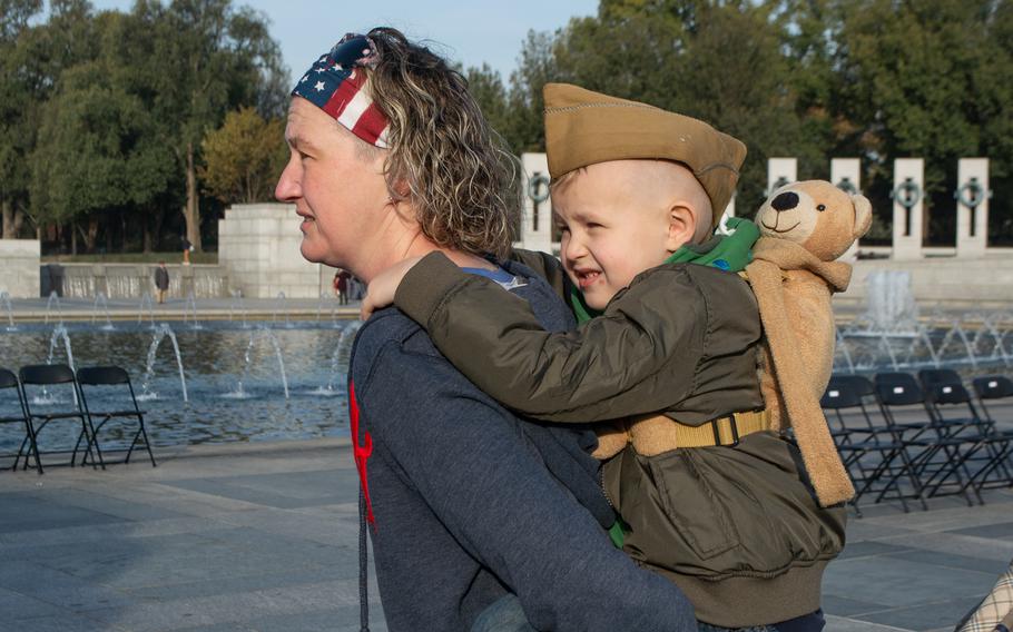 Ryver Witherington enjoys a piggy back ride from his mother, Karen, before the start of the Veterans Day ceremony at the World War II Memorial in Washington, D.C., on November 11, 2019. They were there to honor World War II veteran Bob Swain, who was one of the men in the Parade of Heroes. 