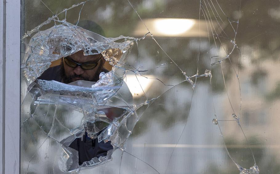 A man is seen through a shattered window at the Department of Veterans Affairs as he cleans up glass in Washington, Monday, June 1, 2020, after a night of protests over the death of George Floyd. Floyd died after being restrained by Minneapolis police officers.