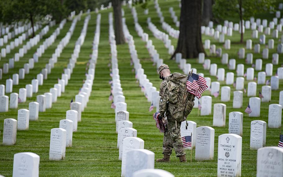 Soldiers place U.S. flags at headstones as part of Flags-In at Arlington National Cemetery, Arlington, Va., on May 21, 2020. 