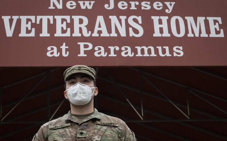 In an April 9, 2020 photo, a New Jersey Army National Guard combat medic stands ready to direct other medics arriving at the New Jersey Veterans Home at Paramus, N.J., to provide medical support for the residents at the home, which is run by the state's Department of Military and Veterans Affairs.