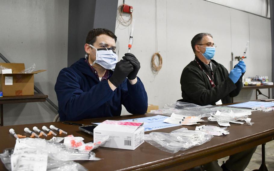 Pharmacists CJ Ludwig, front, and Chris Elizagaray, back, pull doses of the coronavirus vaccine from vials at a Department of Veterans Affairs vaccination clinic on Tuesday, March 2, 2021. 