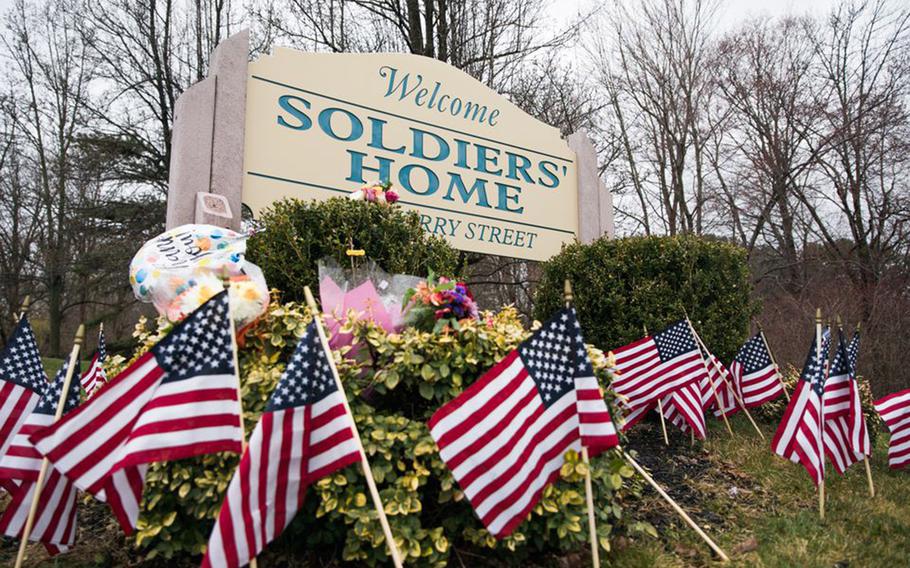 Mini flags and balloons are placed around a sign at Holyoke Soldiers' Home in honor of the veterans who have died because of COVID-19 and to remember their service to the country.