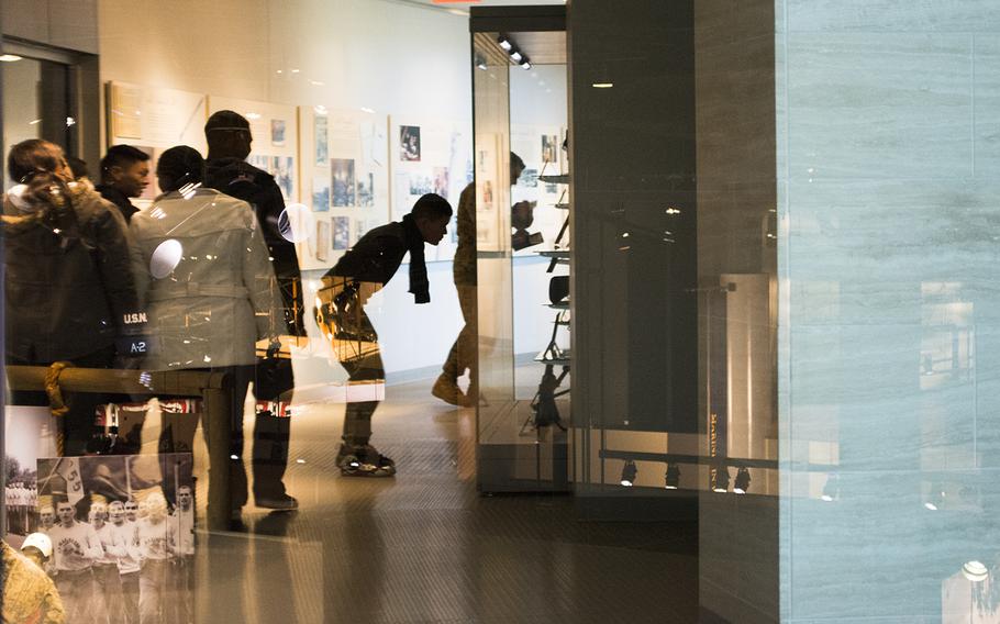 Guests tour the National Museum of the Marine Corps on Feb. 20, 2015. Their images are reflected in glass. 