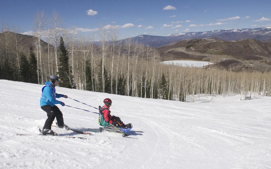 Army veteran Shanda Taylor-Boyd heads down the mountain with the help of an instructor during the National Disabled Veterans Winter Sports Clinic at Aspen Snowmass Resort in Colorado in April 2015.