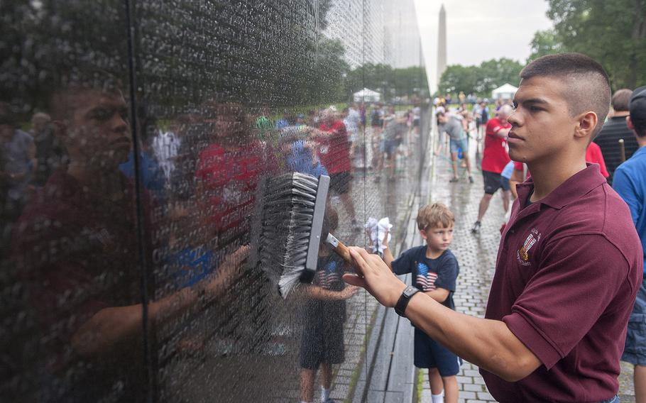 Jared Filcen, 19, an ROTC cadet at Virginia Tech., scrubs a granite panel Saturday, June 20, 2015, at the Vietnam Veterans Memorial Wall, where he joined dozens of volunteers for an early morning wall washing.