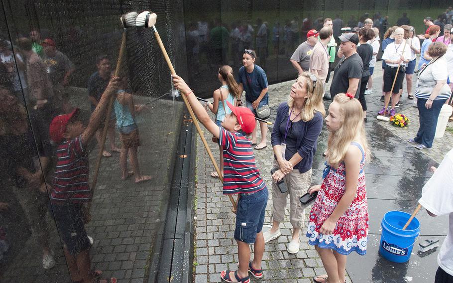 Matthew Luepke scrubs a granite panel at the Vietnam Veterans Memorial Wall on June 20, 2015, as his mother Colleen Shine and his sister Chiara Luepke look on. Shine, daughter of Air Force veteran Anthony C. Shine, and her two children joined dozens of volunteers for an early morning wall washing at the memorial on Saturday.