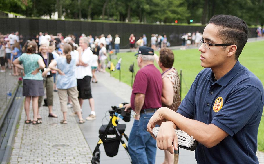 Stephan Acevedo, 20, an ROTC cadet at Virginia Tech, looks at the etched name of his grandfather, Army veteran Jose L. Montes, at the Vietnam Veterans Memorial Wall on Saturday, June 20, 2015. Acevedo joined dozens of volunteers for an early morning Wall washing, a task he has volunteered to do regularly since he was 9.