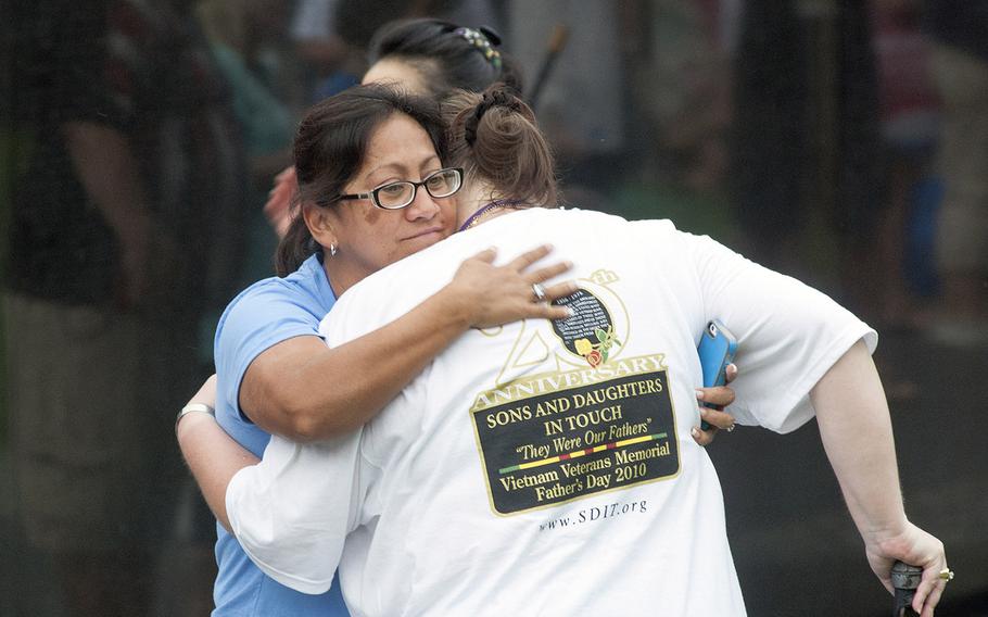Hugs are exchanged as volunteers gather at the Vietnam Veterans Memorial Wall for an early morning wall washing on June 20, 2015.