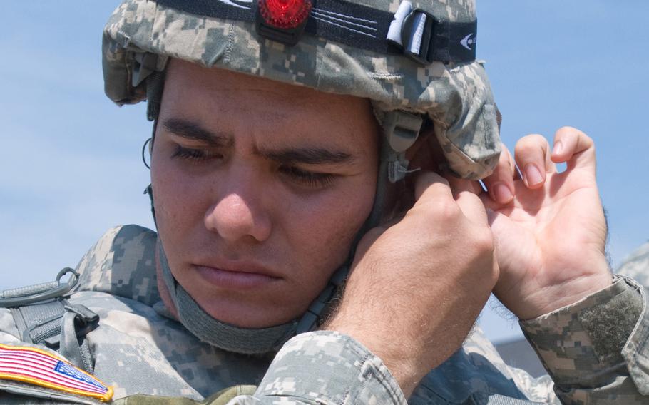Spc. Coca Temoananui, assigned to the 311th Signal Command, puts in ear protection prior to a helicopter flight, in 2012.  