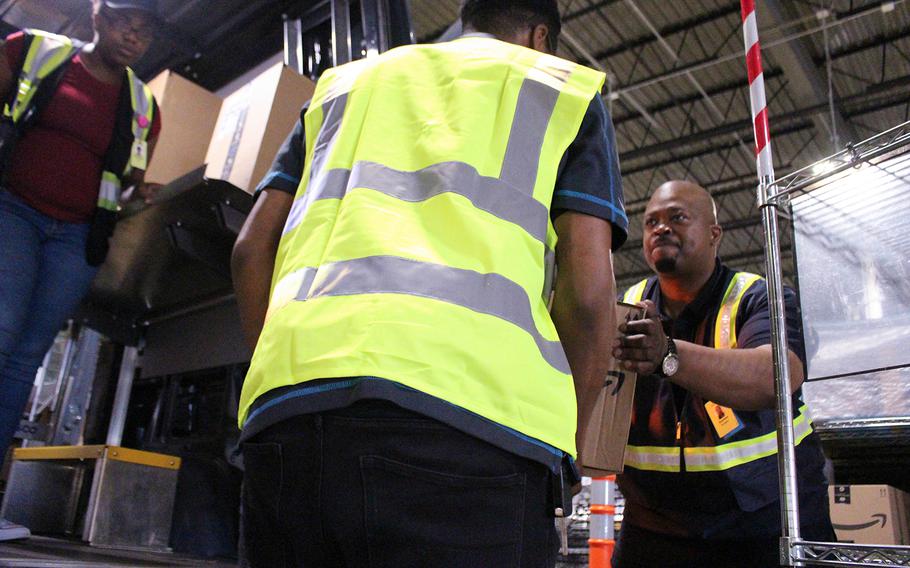 Retired Army Maj. Quinton Burgess (right) helps load items into his truck to be delivered at an Amazon shipping plant in Richmond, Va. Burgess and his Alligiance Logistics LLC company has partnered with Amazon as part of a program that helps veterans become entrepreneurs.