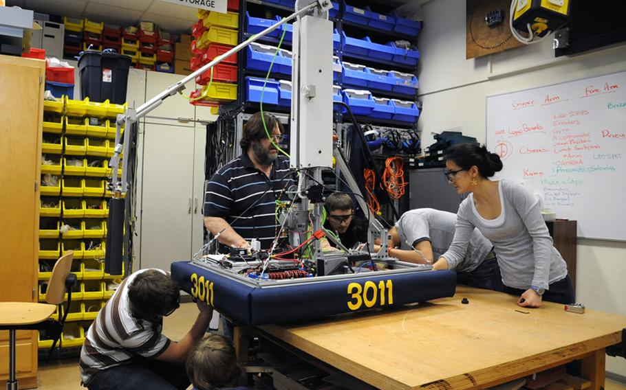 Wiesbaden robotics club adviser Frank Pendzich, center, watches as Tim Kanser, Riley Pickering, Kenny Philips, Dhillon Tisdale and Shena Cousens, from left, attach skirting the the RoboWarriors' robot as they get it ready to be shipped off to Las Vegas for the FIRST Robotics Competition.