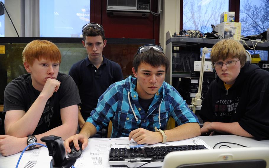 Drew Parker, John Gerber and James Krog, from left, watch Eric Howard, second from right, copy the robot's code for programming, as Wiesbaden High School's RoboWarriors robotics club members put the final touches on their robot before shipping it off to the FIRST Robotics Competition in Las Vegas.
