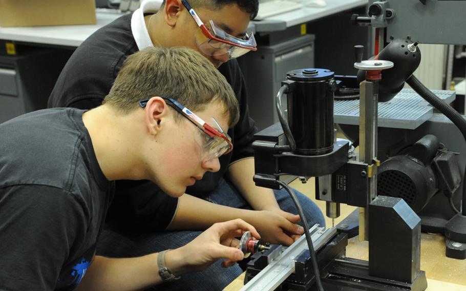 Matthew Garcia, right, watches Chris Bradford make a slot for a rod that will launch a minibot from the RoboWarriors' robot that they are entering in this year's FIRST Robotics Competition in Las Vegas. Vilseck high school&#39;s robotics club is assisting Wiesbaden's this year by building the minibot.