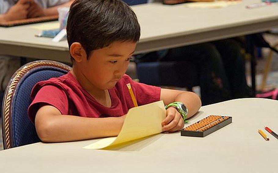 Shoma Ennis, a 2nd grader from Ikego Elementary School, concentrates during the sorobon competition at the New Sanno Hotel in Tokyo on Wednesday.